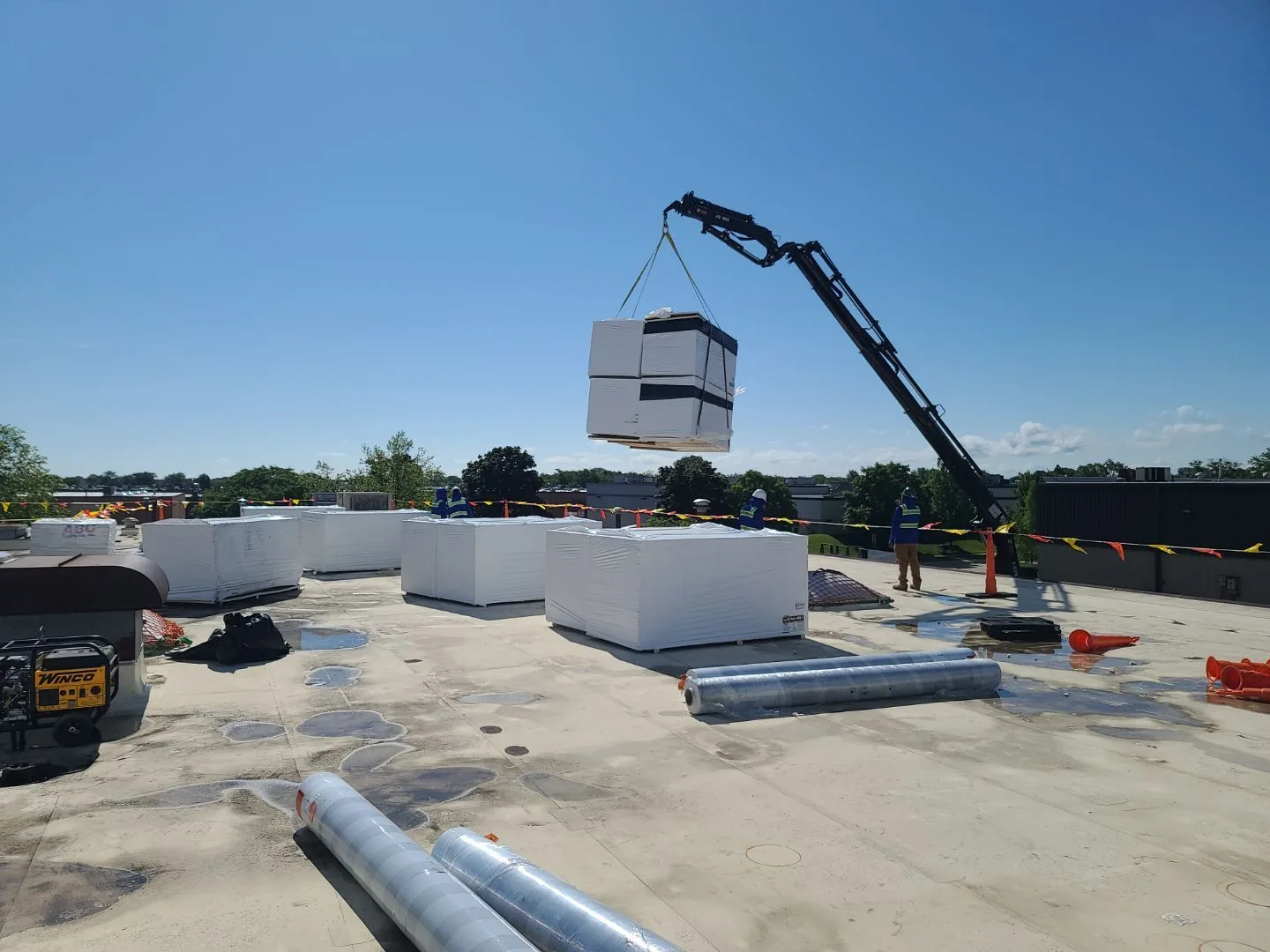 Boom truck delivering insulation pallets to commercial roof during Americanstruction replacement project