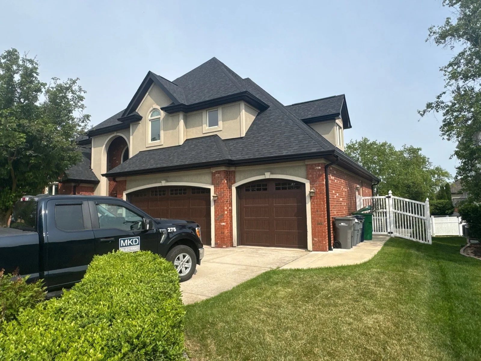 New black seamless aluminum gutters and downspouts installed on a brick Orland Park home by Americanstruction to protect the foundation from water damage