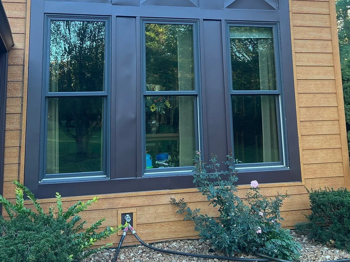 Dark-framed double-hung replacement windows installed on a New Lenox home by Americanstruction